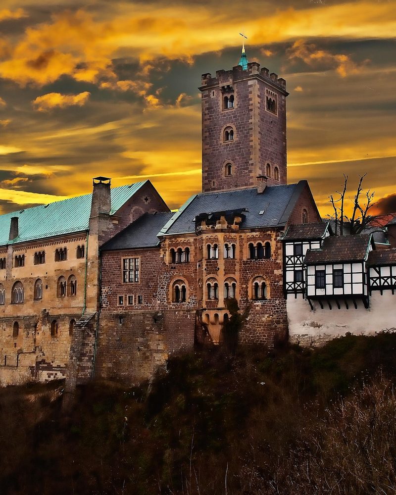 Wartburg Castle sopra Eisenach, Turingia — un castello romanico su un crinale boscoso, dove Martin Lutero tradusse il Nuovo Testamento nel 1521–22 e dove visse Sant'Elisabetta d'Ungheria nel XIII secolo. Patrimonio UNESCO 1999.